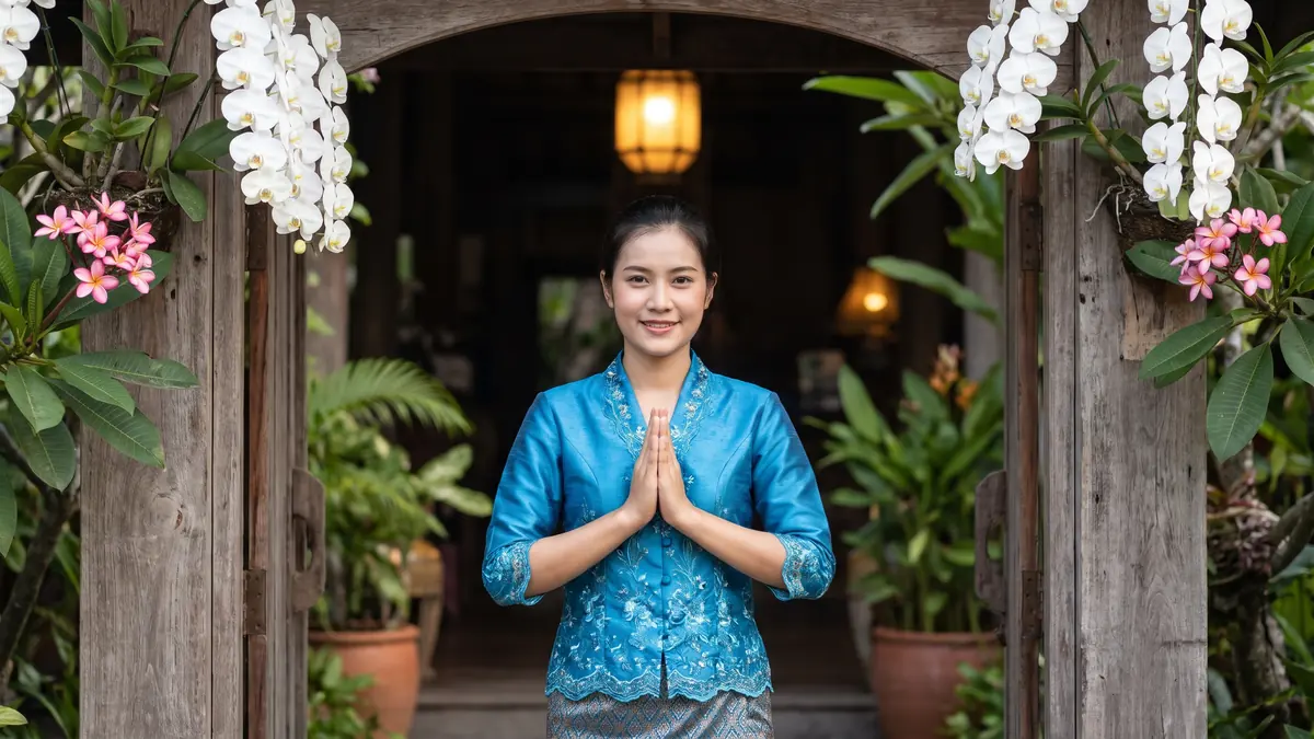 Une hôtesse thaïlandaise salue d’un wai, mains jointes, à l’entrée d’un hôtel