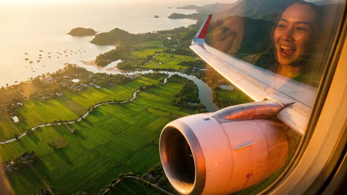 Une voyageuse sourit au hublot d’un avion qui survole des rizières en terrasses