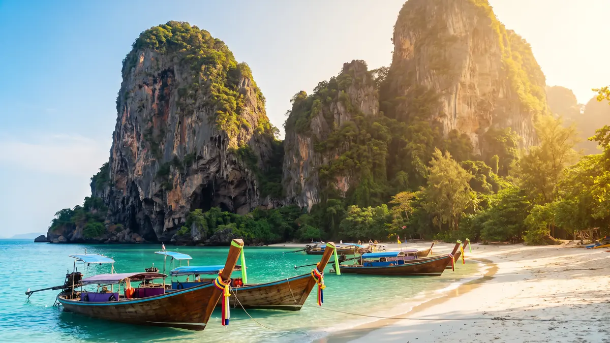 Bateaux longue-queue devant les falaises calcaires de Railay, à Krabi